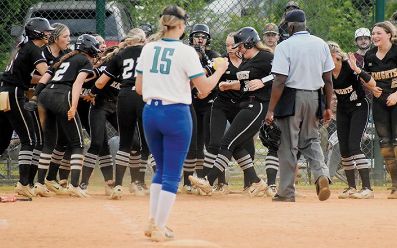 The Lady Knights wait for Sophie Roberts to touch home plate before mauling her in celebration, after the  sophomore hit what proved to be the game-winning, two-run homer in the top of the seventh inning Friday.